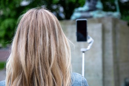 Frau von hinten fotografiert sich mit Selfie-Stick