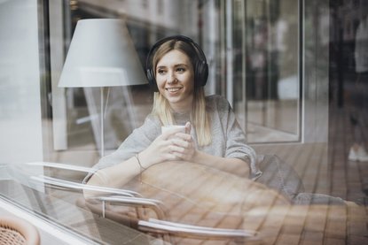 Junge Frau mit Kopfhörern hört einen Podcast 