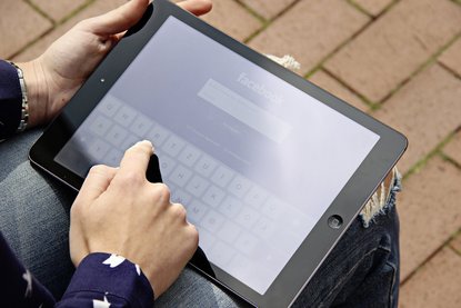 Person meldet sich über ein iPad bei Facebook an