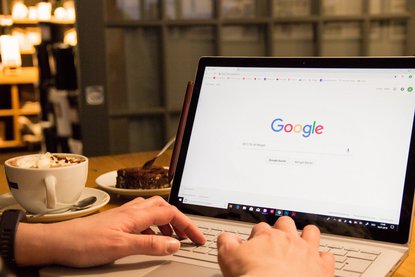 Person tippt auf dem Laptop eine Suche in Google ein
